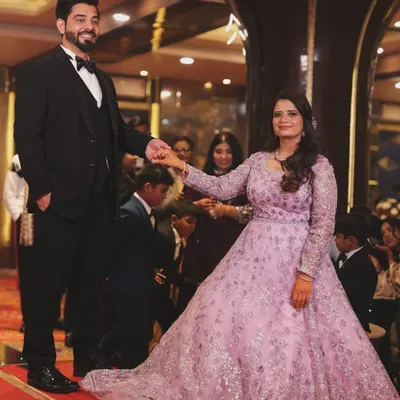Capturing the grand entrance at a reception or engagement party. The groom leads his bride onto the dance floor, her flowing lavender gown creating a beautiful sense of motion. This shot captures the excitement and fairytale quality of the evening.