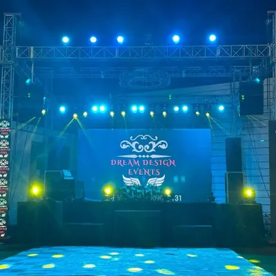 A clean and powerful stage setup ready for a corporate event. This features a large central LED wall for branding, flanked by vertical light arrays and a professional sound system, ensuring your message is seen and heard clearly.