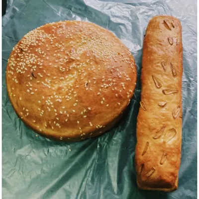 Our freshly baked, homemade breads. On the left is a round Sheermal Naan topped with sesame seeds, and on the right is a loaf of savory garlic bread, both perfect for soaking up our rich curries.