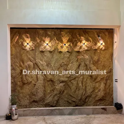 The finished stone mural for the fountain wall, complete with custom light fixtures. Before the water is turned on, you can see how the lighting highlights the deep, rugged texture we created by hand.