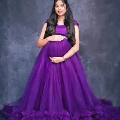 A full-length portrait in a royal purple tulle gown against a simple grey studio backdrop. This allows the vibrant color and design of the dress to be the main focus.