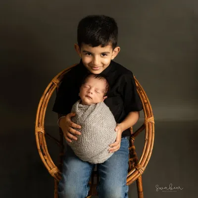 A proud big brother holds his newborn sibling. Capturing the start of this lifelong bond is one of the most special parts of my job.