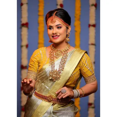 A classic South Indian bridal look for a photoshoot, featuring a beautiful tissue silk saree. I created a warm, golden look with defined eyes and traditional jewelry placement to capture the essence of our heritage.