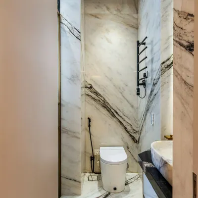 A glimpse into a bathroom ensuite defined by dramatic black and white book-matched marble. The design features a smart toilet and a heated towel rack, combining opulence with modern comfort.