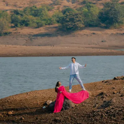 The ultimate Bollywood pose. With his arms outstretched and her vibrant pink saree flowing, this shot is a direct homage to the grand, romantic scenes of Indian cinema.