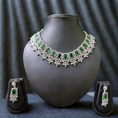A stunning diamond-look necklace set for the modern bride. This piece features brilliant emerald-green stones set in a silver-tone finish, complete with matching drop earrings.