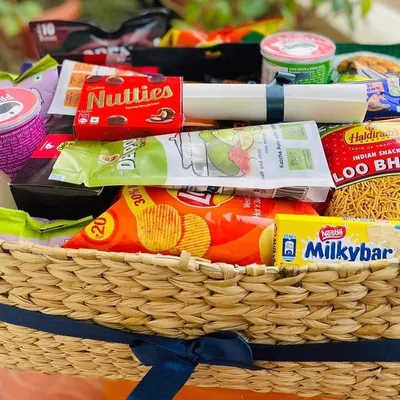 A classic snack lover's dream. This wicker basket is overflowing with a wide assortment of popular Indian snacks and chocolates, including Lays, Haldiram's Loo Bhujia, Nutties, and Milkybar. It's the perfect treat for any casual occasion.