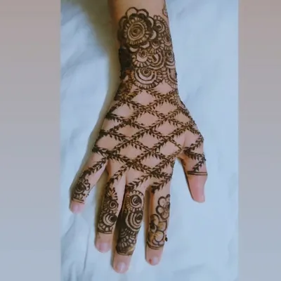 A classic Indian 'jaal' or net pattern on the back of the hand. This design is created with delicate crisscrossing vines and is surrounded by a detailed floral border.