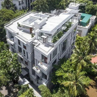 An aerial view of the Boat Club Apartments in Chennai, showing how the building's form is broken down into smaller volumes to reduce its mass and integrate with the surrounding green landscape.