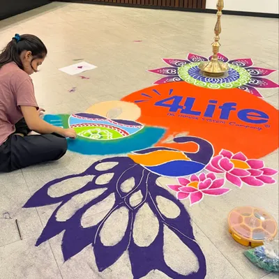 Here I am working on a large-scale corporate rangoli. You can see the design is first outlined and then carefully filled with different shades of colored powder to create the final image.