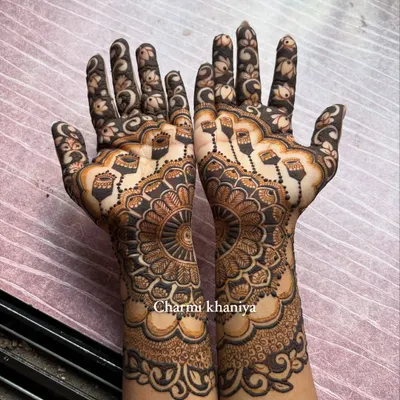 A beautiful henna design featuring a large, intricate mandala. The hanging 'jhumka' or earring motifs add a festive and celebratory touch, perfect for Karwa Chauth or Eid.