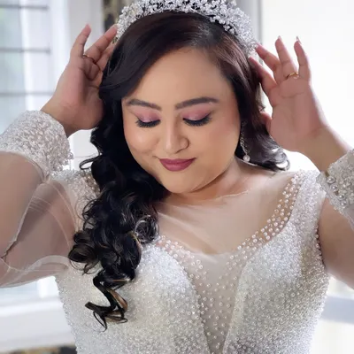 A beautiful Christian bride adjusting her tiara. The makeup is soft and romantic, with pink eyeshadow and a matching lip colour.