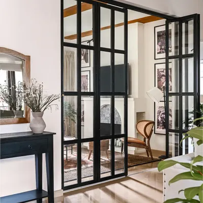 The entryway of the Modern Spanish Home makes a statement from the moment you walk in. I designed these giant black iron and glass bi-fold doors to separate the living and family rooms, creating privacy without closing off the space entirely.