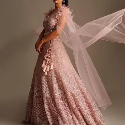 Modern, chic, and perfect for a bridesmaid or engagement party. This light pink net lehenga with a feathered blouse and flowing dupatta is a true fashion statement.