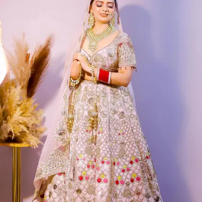 A stunning full-length portrait of the bride in her magnificent lehenga. The soft lighting and her serene expression capture her elegance and grace on the wedding day.