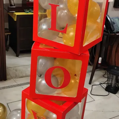 I use creative props like these stacked 'LOVE' boxes to add a unique touch to your celebration. The transparent boxes are filled with gold and silver balloons to match the party's theme.