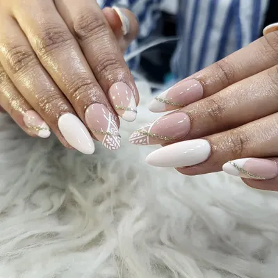 A beautiful and sophisticated set we designed for an engagement. This look features a mix of solid white and nude nails with delicate, hand-painted white patterns and a subtle gold glitter line for a touch of celebration.