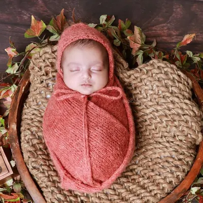 A portrait of one of the twins from a vintage-themed session, wrapped in a warm, rust-colored swaddle. We capture individual portraits in addition to shots of the pair together.