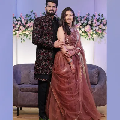 A classic full-length portrait of the couple at their reception, looking elegant and happy against a floral backdrop.