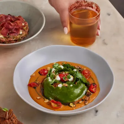 This is one of our most popular bowls: the Spinach and Ricotta Crown Ravioli. The unique shape holds a delicate filling, perfectly complemented by a charred tomato and miso sauce, toasted walnuts, and creamy goat's cheese.