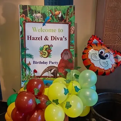 A personalized welcome sign for a jungle-themed 5th birthday party. The sign is complemented by a small balloon cluster and an animal-shaped foil balloon to set the theme from the entrance.