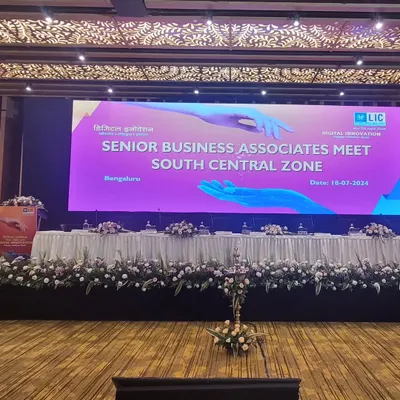 Our stage design for the LIC Senior Business Associates Meet at Taj Yeshwantpur, featuring a wide LED screen and elegant floral decor.