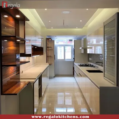 This parallel kitchen showcases a stunning blend of high-gloss white cabinetry and rich wood shelving. The layout maximizes storage and workspace in a narrow area, with reflective surfaces and good lighting creating a sense of openness.