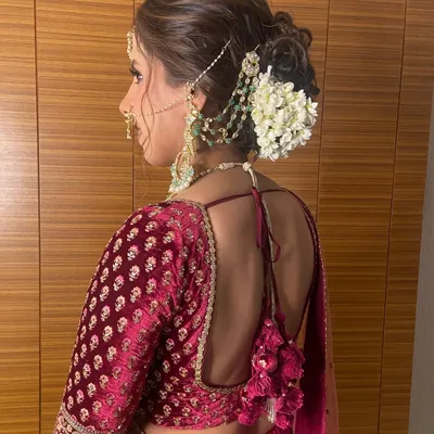 A classic messy bun adorned with a string of fresh gajra (jasmine flowers). This is a timeless choice for a traditional Indian wedding ceremony, offering a beautiful fragrance and a classic bridal feel.