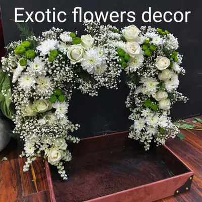 A large floral arch designed for event decor or as a frame for a gift hamper. This piece is crafted with white roses, chrysanthemums, and baby's breath, creating a lush and impressive display.