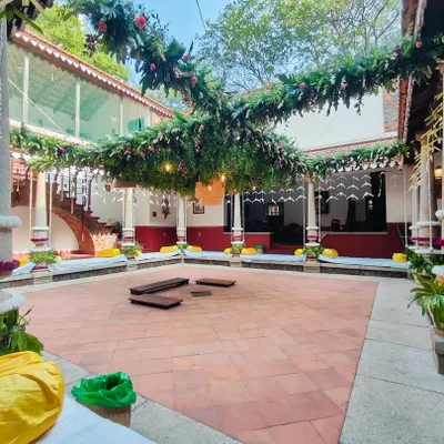 We decorated this beautiful heritage home's courtyard for a traditional wedding ceremony. The setup features lush green foliage garlands crisscrossing the open space, with floral accents and traditional pillar wraps, creating an elegant and natural ambiance for the wedding rituals.