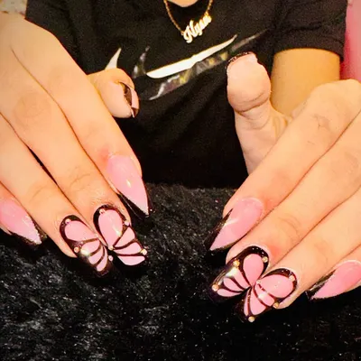 A close-up of my popular butterfly design. I use a sheer pink base on stiletto nails and hand-paint these delicate wings, outlined in black with tiny gold stud details for a touch of sparkle.