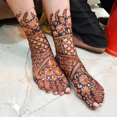This is a classic bridal feet design, covering the entire foot with a mix of floral and jaali (net) patterns. The design is symmetrical and ensures the bride's feet look beautiful from every angle.