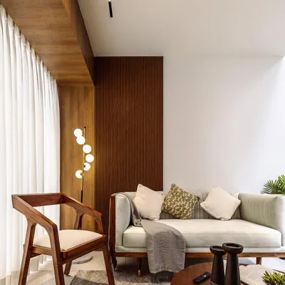 A beautifully lit living room corner, featuring a modern wooden armchair and a sleek sofa. This shot highlights the warm and inviting atmosphere created by the blend of natural textures and contemporary furniture.