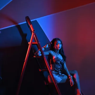 A shot that screams confidence. The ladder, the pose, the red and blue lighting, it all comes together to create a powerful, edgy look.