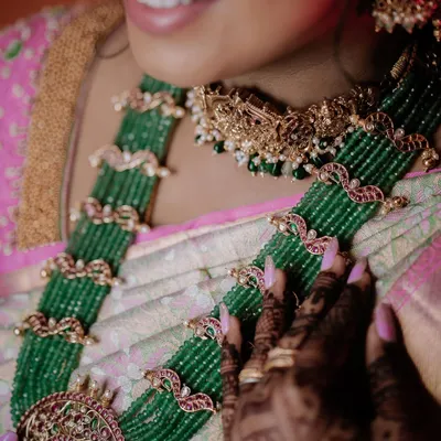 A close-up of a bride's stunning green beaded necklace and the intricate details of her saree.