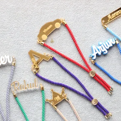 A vibrant collection of our personalized acrylic Rakhis. You can customize them with names, initials, or fun shapes like cars and crowns, making each one truly unique.