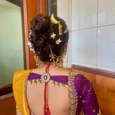 A detailed view of a traditional Marathi Khopa, or bridal bun, adorned with a classic chandrakor moon accessory and other delicate gold pins.