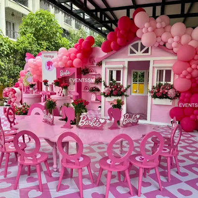 A full view of the ultimate Barbie party, featuring a custom dreamhouse, themed tables and chairs, and an abundance of pink balloons.