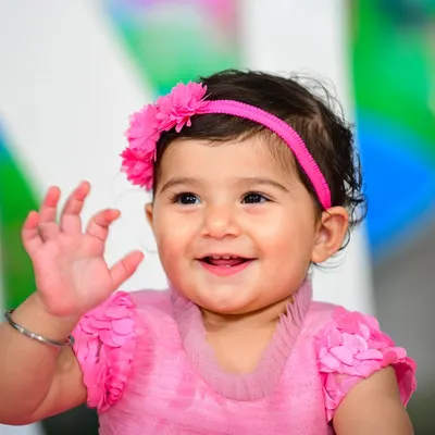 A happy wave from the birthday girl! This close-up shot captures her bright smile and cheerful personality on her first birthday.