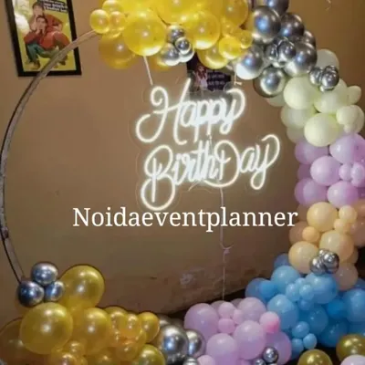 A circular ring backdrop with a 'Happy Birthday' neon sign and a colorful balloon garland is a popular choice for birthday parties and can be customized with any color scheme.