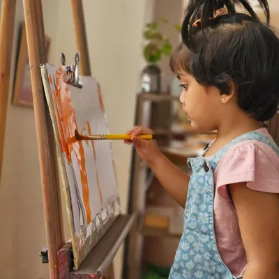 A young artist lost in her work at the easel. We provide open-ended art materials so children can explore colors, textures, and their own creativity without a predetermined end product.