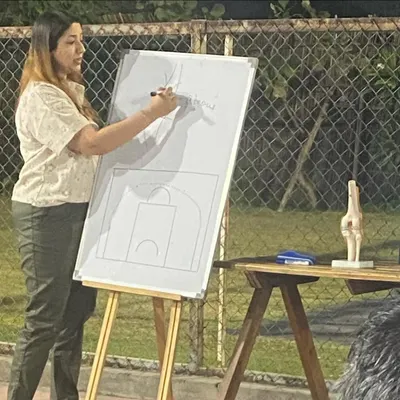 Dr. Kavita Goel leads an interactive session on injury prevention. She is explaining key concepts on a whiteboard, helping our athletes understand their bodies better.