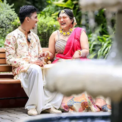A moment of pure, unrestrained laughter during a Haldi ceremony, captured near a garden fountain.