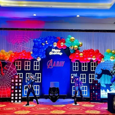 Avengers assemble for Aarav's 5th birthday. This superhero stage features a city skyline backdrop, character cutouts of Black Panther and Vision, and themed props like Iron Man's helmet and Captain America's shield.