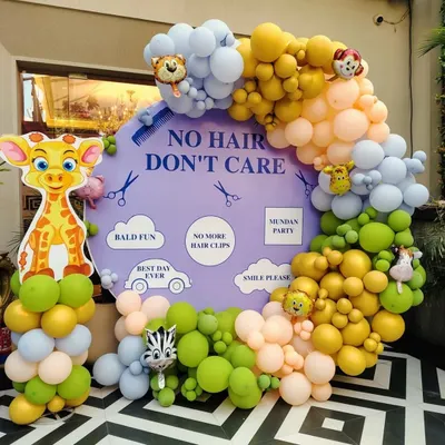 A fun and cheeky photo booth for a Mundan ceremony. The "No Hair, Don't Care" theme is brought to life with a custom backdrop surrounded by a playful jungle-themed balloon garland, creating a perfect spot for happy pictures.