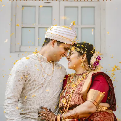 A beautiful, candid moment between Rakshith and Dhanya, showered in golden petals. This fine-art portrait captures their connection, with the bride's traditional red Kanjeevaram saree and temple jewelry shining through.