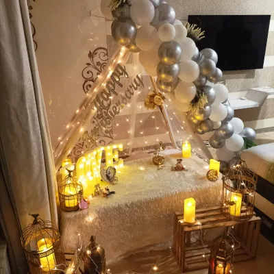 A romantic anniversary surprise at home. This beautiful cabana tent setup is decorated with white and silver balloons, fairy lights, and candle-lit lanterns, creating a magical and intimate atmosphere.