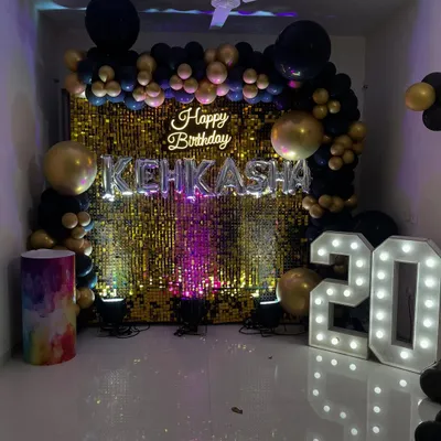 A stunning gold shimmer wall serves as the centerpiece for this 20th birthday. Paired with a neon sign and a black and gold balloon arch, it creates an unforgettable photo backdrop.