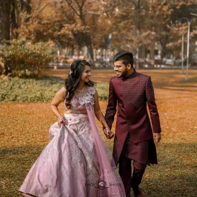 A classic engagement portrait of the couple walking hand-in-hand through a park. Their elegant ethnic wear and the beautiful autumn colors create a timeless and romantic image.
