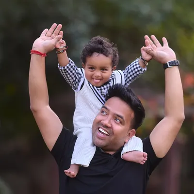A fun and energetic shot of a boy on his dad's shoulders, reaching for the sky. This pose is always a favorite for capturing the playful side of the father-son relationship.